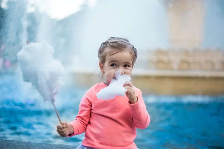 Young child eating pink candy floss at a party