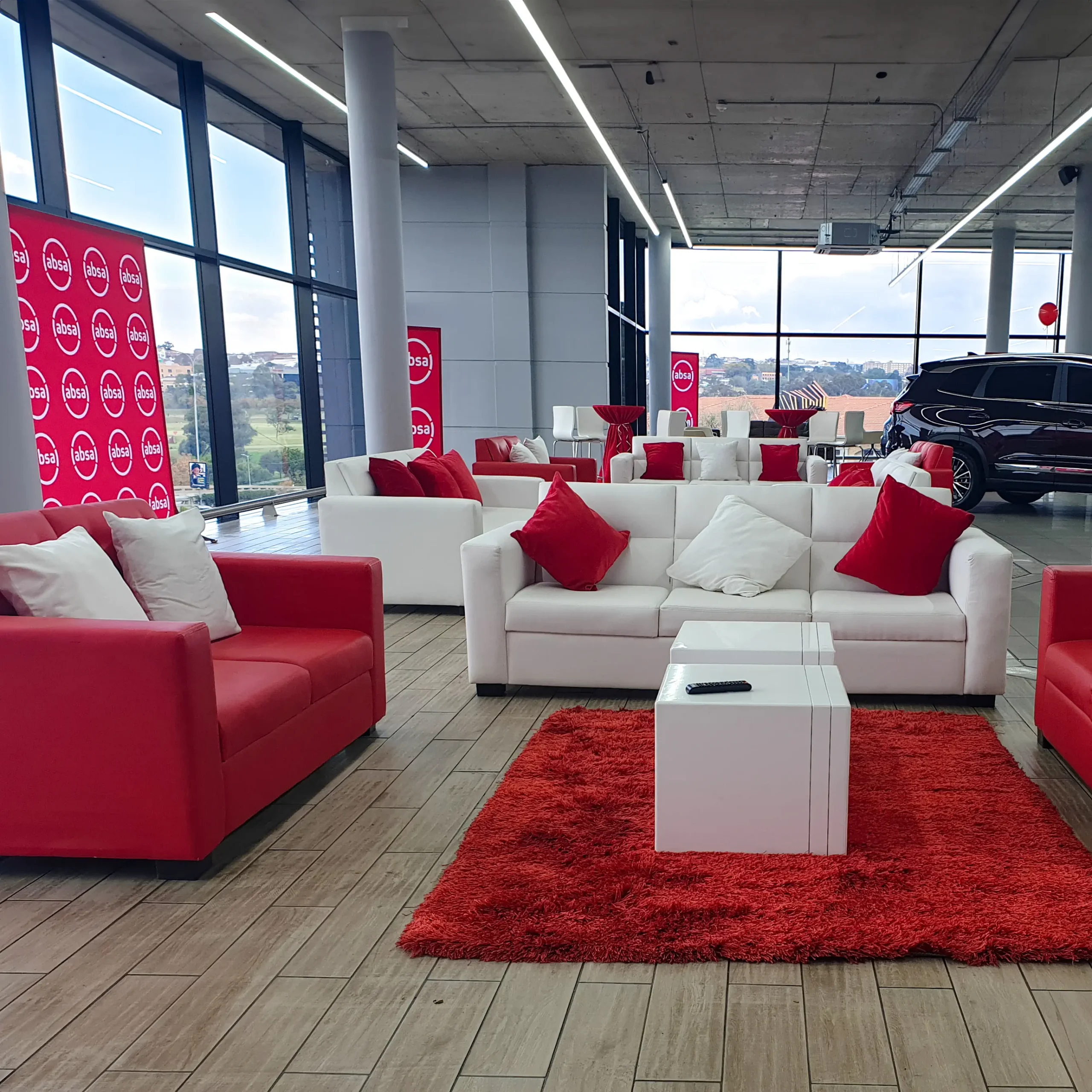 Red and white corporate lounge furniture setup for an Absa event