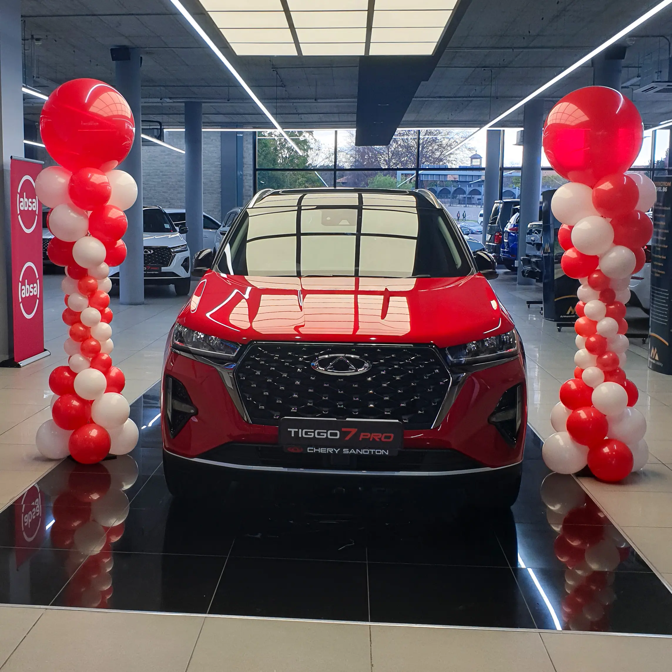 Red and white balloon columns framing a Chery vehicle display