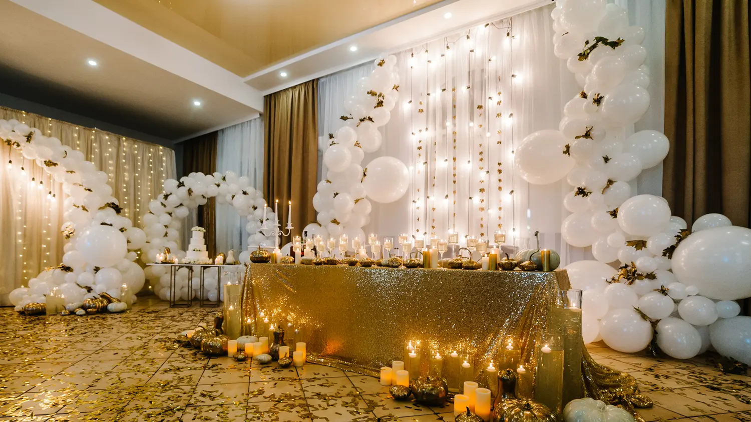 White and gold balloon garlands with candlelit event table décor